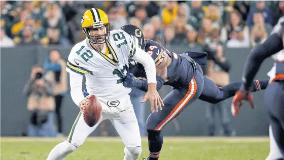  ??  ?? Packers quarterbac­k Aaron Rodgers, No.12, tries to run away from the Bears’ Leonard Floyd.