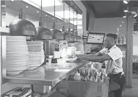  ?? JOE RONDONE/THE COMMERCIAL APPEAL ?? Waiter Johnathan Williams grabs a breakfast dish from the service counter at Tenero Cafe + Butcher in East Memphis Friday.