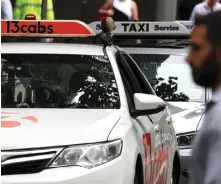  ?? — AFP photo ?? A pedestrian walks past a row of taxis in central Sydney on March 18. More than 8,000 taxi drivers and hire car owners banded together to launch legal action in 2019, arguing they lost substantia­l income when Uber entered Australia in 2012.