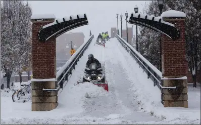  ?? AP/The Roanoke Times/STEPHANIE KLEIN-DAVIS ?? Workers in Roanoke, Va., plow and shovel snow from the Martin Luther King Bridge on Sunday as the winter storm moves through the Southeast.