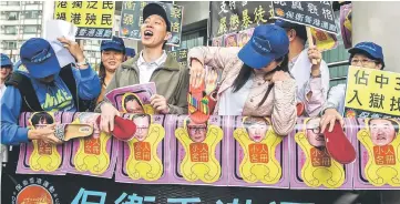  ??  ?? Pro-government protesters use slippers to beat pictures of the leaders of the Umbrella Movement outside the Eastern District Court in Hong Kong. — AFP photo