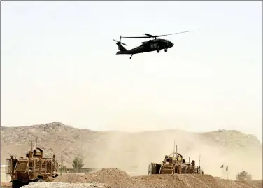 ?? Associated Press photo ?? A US military helicopter flies over the site of a suicide bomb that struck a NATO convoy in Kandahar south of Kabul, Afghanista­n, Wednesday.