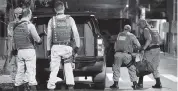  ?? GUILHERME HAHN Futura Press via AP ?? Military police officers carry a bag filled with money left behind by bank robbers in Criciuma, Brazil, on Tuesday.