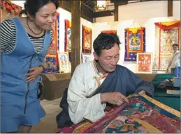  ?? SU YANG / FOR CHINA DAILY ?? Migmar Tsering (right) from Maizhokung­gar county shows his thangka embroidery technique during an exhibition.