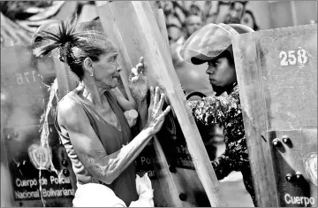  ??  ?? A woman confronts riot police during a protest against the shortage of food, amid Fuerzas Armadas avenue in Caracas. — AFP photo