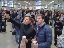  ?? MARK LENNIHAN, AP ?? Passengers check a schedule board Monday while waiting in New York’s Penn Station. A New Jersey Transit train derailed while pulling into the station at slow speed.