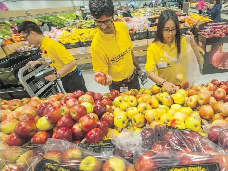  ?? ARLEN REDEKOP/FILES ?? Staff pick out fruit at a Loblaw-owned Real Canadian Superstore in Vancouver for a “click-and-collect” online grocery order. Loblaw is watching the home delivery trend, though research suggests there is a shift toward click-and-collect among consumers.