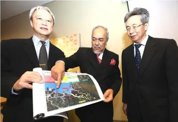  ??  ?? Asfia (centre) pointing at the overall plan and work packages for the proposed second trunk road map while flanked by Ng (left) and Chai. — Photo by Chimon Upon