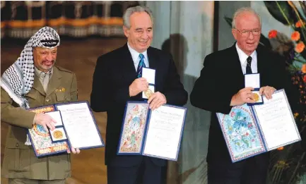  ?? (Jerry Lampen/Reuters) ?? Yasser Arafat, Shimon Peres and Yitzhak Rabin show their shared Nobel Peace Prize awards to the audience in the Oslo City Hall in December 1994.