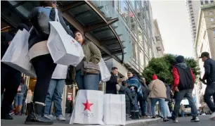 ?? — Bloomberg ?? Shoppers with Macy’s shopping bags wait on a kerb in San Francisco.