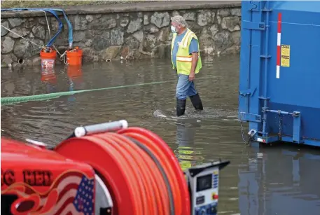  ?? MATT sTonE pHoTos / HErAld sTAFF ?? STILL WET: Workers continue to pump out Norwood Hospital on Monday after torrential rains Sunday flooded the hospital and parking lot.