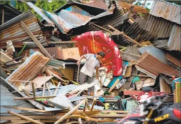  ?? Bay Ismoyo AFP/Getty Images ?? A MAN looks over his destroyed home in Palu, which was devastated in the quake and tsunami in Indonesia.