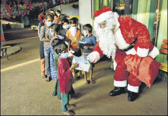  ?? PRAFUL GANGURDE/HT ?? A man dressed as Santa Claus distribute­s gifts to children of Signal School in Thane.