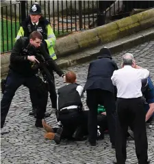  ?? Photo: PA ?? A policeman points a gun at a man on the ground as emergency services attend the scene of the attack outside the Palace of Westminste­r in London.