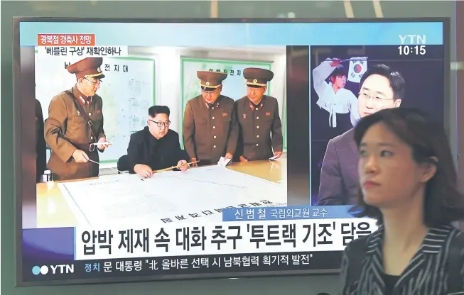  ?? — Gambar AFP ?? TANGGUH SAJA: Seorang wanita melintasi skrin televisyen memaparkan berita mengenai Kim menerima taklimat mengenai pelan serangan misil ke Guam, di sebuah stesen kereta api di Seoul, semalam.