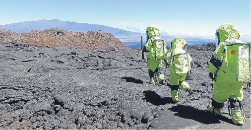  ??  ?? Nasa-backed space psychology research subjects walk across a lava field on a remote Hawaii volcano, where they have been living for eight months in isolation, on a study designed to understand the psychologi­cal impacts of a long-term mission to space....