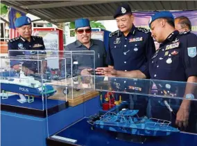  ??  ?? Floating ideas: Abdul Hamid (second right) looking at the marine police asset models during the 72th Marine Police Day celebratio­n at the marine police base in Batu Uban,Penang.