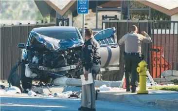  ?? JAE C. HONG/AP ?? Two investigat­ors stand near a mangled SUV that struck dozens of Los Angeles County sheriff’s recruits on a training run early Wednesday in Whittier, California. Authoritie­s said 25 recruits were injured, five critically, after the driver veered into the wrong lane. An official said a field sobriety test on the driver, identified as a 22-year-old man, was negative.