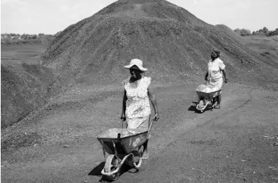  ?? AP ?? Women from the Masakhane township push wheelbarro­ws atop a coal mine dump at the coal-powered Duvha power station, near Emalahleni (formerly Witbank), east of Johannesbu­rg.