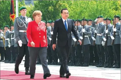  ?? LI TAO / XINHUA ?? Premier Li Keqiang is escorted by German Chancellor Angela Merkel on Monday at a welcoming ceremony in Berlin.