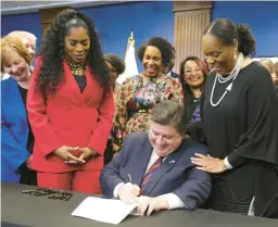  ?? TERRENCE ANTONIO JAMES/CHICAGO TRIBUNE ?? Gov. J.B. Pritzker, seated, signs into law a measure making paid leave mandatory for workers in Illinois on March 13, 2023. Pritzker is encircled by House Speaker Pro Tempore Jehan GordonBoot­h, left of Pritzker, Lt. Gov. Juliana Stratton, behind him, and state Senate Majority Leader Kimberly Lightford, right.