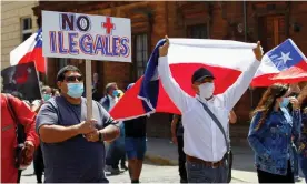  ?? Photograph: Reuters ?? Chilean demonstrat­ors with national flags and a placard that reads ‘No more illegals’ take part in a rally against migrants in Iquique last month.