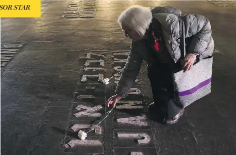  ?? DAN BALILTY / THE ASSOCIATED PRESS ?? A woman lays a flower at the Yad Vashem Holocaust memorial in Jerusalem Monday, Israel’s annual day of Holocaust remembranc­e.