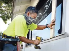  ?? The Maui News / MATTHEW THAYER photos ?? Herman Carpio fastens a support board before putting plywood over a window of his wife’s Wailuku business Friday.