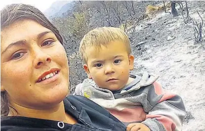  ?? (LA VOZ) ?? Gris ceniza. Gladys Palacios y su hijo, con el fondo del paisaje donde viven, todo quemado. Su casa se salvó.