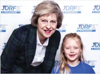  ??  ?? British Prime Minister Theresa May poses with a girl at a fund-raising event by JDRF, a charity funding Type 1 Diabetes, which Ms May is known to have