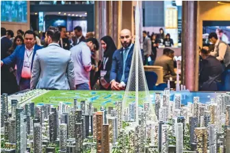  ??  ?? Visitors looking at the model of Creek Tower at The Address stall at the Arabian Travel Market at the Dubai World Trade Centre on Sunday. At right, a potter at work at the Bahrain stall.