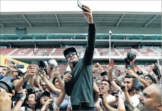  ??  ?? EXPECTACIÓ­N. Fernando Alonso se hace un ‘selfie’, en el circuito de Montmeló, con todos los admiradore­s que reclaman su atención.