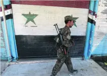  ?? Rodi Said / Reuters ?? A Kurdish fighter from the People’s Protection Units against a backdrop of the Syrian national flag in Qamishli city.