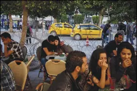  ?? TODD HEISLER / THE NEW YORK TIMES FILE (2012) ?? Customers sit May 10, 2012, at a cafe’s sidewalk tables, surrounded by razor wire to keep out protesters, near the Interior Ministry in Tunis, Tunisia. Tunisia, hailed as the sole success of the popular Arab Spring uprisings, has struggled to reap the benefits of democracy as its economy founders.