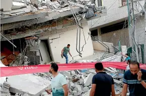  ?? AP ?? People inspect the rubble of a destroyed residentia­l building that was hit by an Israeli airstrike, in Gaza City.