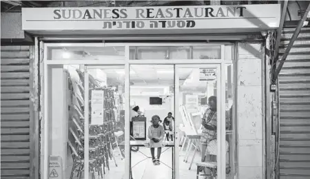  ?? ODED BALILTY/AP 2020 ?? A Sudanese migrant family in a closed restaurant in south Tel Aviv, Israel. Many of the migrants find it a struggle to make ends meet.