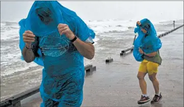  ?? COURTNEY SACCO/CORPUS CHRISTI CALLER-TIMES ?? People try to walk Saturday in Corpus Christi, Texas. Hurricane Hanna made landfall south of there in Port Mansfield.