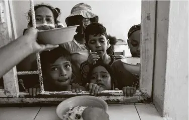  ?? Nicolo Filippo Rosso / Bloomberg ?? Migrants and asylum seekers receive food at a shelter in Tapachula in Mexico’s Chiapas state last month.