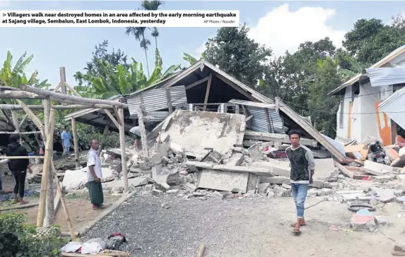  ?? AP Photo / Rosidin ?? > Villagers walk near destroyed homes in an area affected by the early morning earthquake at Sajang village, Sembalun, East Lombok, Indonesia, yesterday