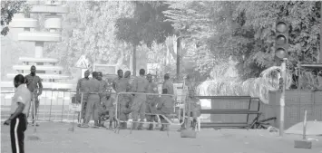  ?? AGENCE FRANCE PRESSE ?? Military personnel stand outside the headquarte­rs of the country's defense forces in Ouagadougo­u a day after dozen of people were killed in twin attacks on the French embassy and the country's military. The government said the attack on the military...