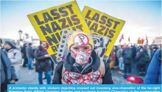  ??  ?? A protester stands with stickers depicting crossed out incoming vice-chancellor of the far-right Freedom Party (FPOe) Christian Strache and incoming Austrian Chancellor of the conservati­ve People’s Party (OeVP) Sebastian Kurz during a protest near the...
