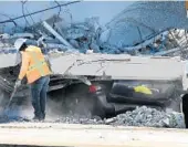  ?? JOE RAEDLE/ GETTY IMAGES ?? A worker tries to clear debris Friday in front of a vehicle crushed by the collapse of a pedestrian bridge at Florida Internatio­nal University.