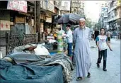  ?? KARAM AL-MASRI/GETTY-AFP ?? Syrians walk by food stalls this month in one of Aleppo’s several rebel-held areas, which have been heavily bombed.