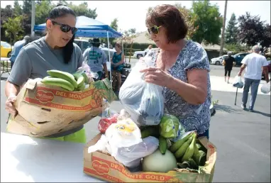  ?? RECORDER PHOTOS BY CHIEKO HARA ?? First time visitors Christine Redwine, left, and Sandra Hurt try to organize boxes full of food items to carry out Friday, Aug. 24 at Burton School District’s Healthy on the Go neighborho­od market. They provide seasonal food items to the community members every fourth Friday of the month at the old Masonic Lodge on West Henderson Ave.