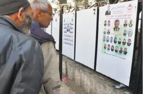  ?? Anis Belghoul / Associated Press ?? Residents of Algiers review posters this month for the May 4 legislativ­e vote.