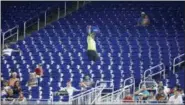  ?? WILFREDO LEE — THE ASSOCIATED PRESS ?? In this Tuesday photo, a vendor walks through a section of mostly empty seats during the first inning of a baseball game between the Miami Marlins and the New York Mets at Marlins Park stadium in Miami.