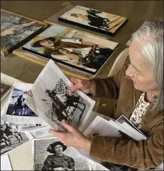  ?? (Arkansas Democrat-Gazette/Sean Clancy) ?? Katherine Strause looks over copies of the vintage photograph­s she uses as references for her paintings.