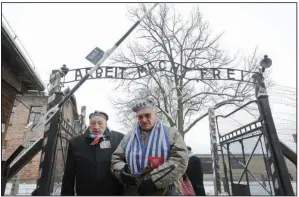  ?? (AP/Alik Keplicz) ?? Holocaust survivors walk outside the gate of the Auschwitz Nazi death camp in Oswiecim, Poland in 2015, 70 years after prisoners there were liberated by the Soviet Red Army. An exhibit in Kansas City, “Auschwitz. Not long ago. Not far away” opened June 14.