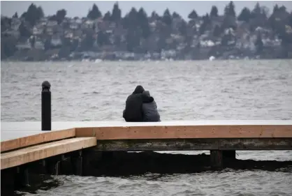  ??  ?? A couple gazes over Lake Washington in Kirkland, Washington. As the coronaviru­s pandemic has spread, officials have advised social distancing from crowds to avoid contractin­g Covid-19. Photograph: John Moore/Getty Images