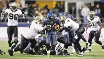  ?? Elaine Thompson / Associated Press ?? Lynch (24) breaks away from a tackle by Saints defenders to score in an NFC wild-card playoff game in 2011. He won his only Super Bowl title with Seattle after the 2013 season.